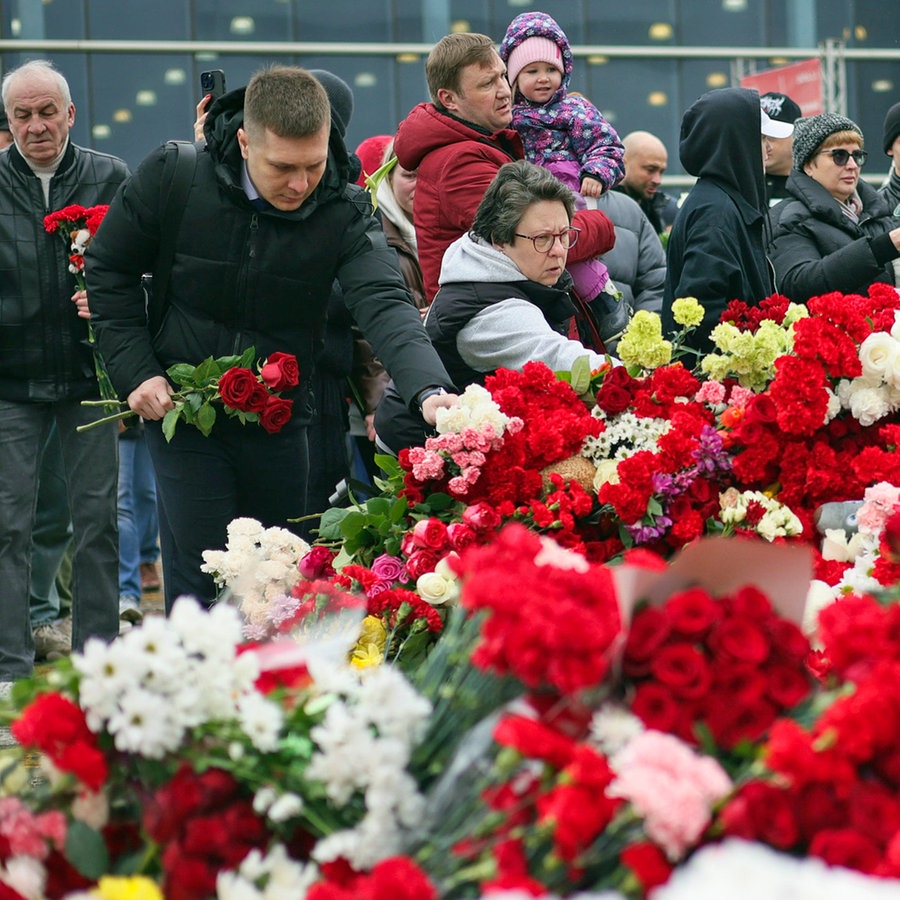 Menschen legen Blumen und Spielzeug am Zaun neben dem Konzertsaal bei Moskau ab, auf den ein Terroranschlag verübt worden war. © Vitaly Smolnikov/AP/dpa 