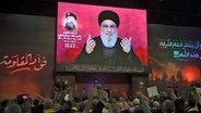 Anhänger jubeln in Beirut (Libanon), während sie eine Rede des Hisbollah-Führers Nasrallah auf einem Bildschirm verfolgen (Archivbild). © AP/dpa Foto: Mustafa Jamalddine