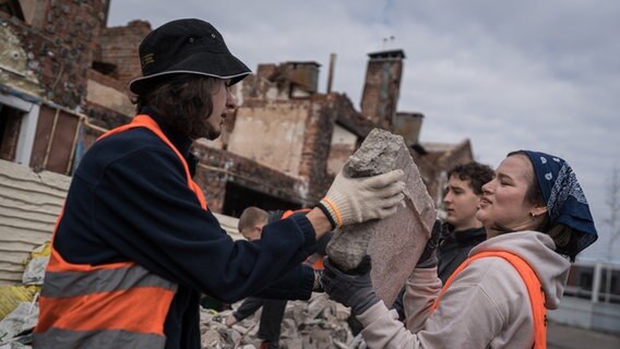 Zwei Helfer der NGO Brave to Rebuild helfen beim Wiederaufbau eines zerstörten Hauses in der Ukraine. © picture alliance Foto: Adri Salido