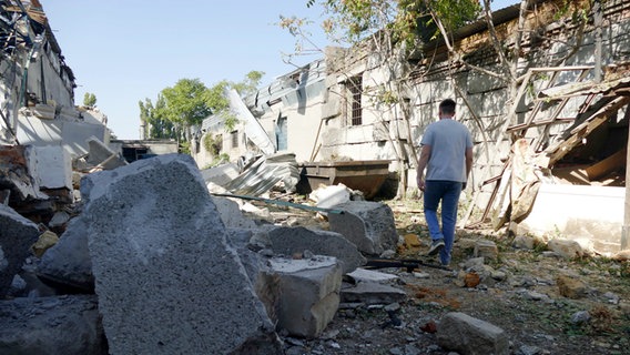 Ein Mann geht durch die Ruinen einer Produktionshalle für Industriegüter in Odessa (Ukraine), die durch russische Raketentrümmer zerstört wurde. © Ukrinform/dpa 
