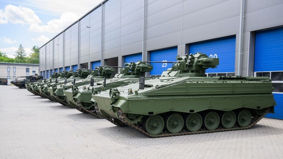 Wieder aufbereitete Marder-Schützenpanzer stehen bei einer Führung durch das Rheinmetall-Werk anlässlich der Sommerreise des niedersächsischen Wirtschaftsministers vor einer Halle. © picture alliance/dpa Foto: Julian Stratenschulte