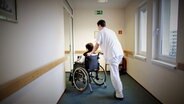 Ein Pfleger schiebt eine Frau im Rollstuhl durch einen Gang © picture alliance / photothek | Thomas Trutschel Foto: Thomas Trutschel
