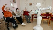 Ein programmierter Roboter führt Bewohnern eines Pflegezentrums Übungen vor. © dpa Foto: Matthias Bein