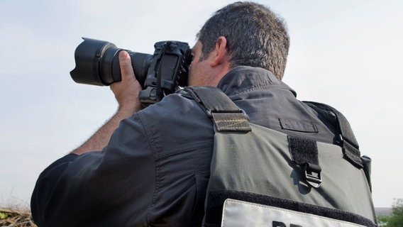 Professioneller Photojournalist mit einer Weste mit Aufdruck "Press" fotografiert. © picture alliance / Photoshot | 