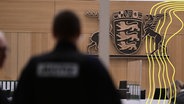 Sicherheitskräfte und Anwälte stehen zu Beginn eines Prozesses vor einem Gerichtssaal vor dem OLG Stuttgart (Symbolbild). © picture alliance Foto: Bernd Weißbrod