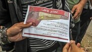 Palästinenser halten ein Flugblatt in der Hand, das von einem Militärflugzeug der israelischen Armee über dem Osten der Stadt Rafah abgeworfen wurde und sie auffordert, die Stadt zu evakuieren. © dpa Foto: Abed Rahim Khatib