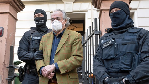 Bei einer Razzia gegen sogenannte "Reichsbürger" führen vermummte Polizisten, nach der Durchsuchung eines Hauses, Heinrich XIII Prinz Reuß (Mitte) zu einem Polizeifahrzeug. © dpa Foto: Boris Roessler