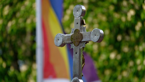 Ein kirchliches Kreuz vor einer Regenbogenfahne. © picture alliance/dpa/Henning Kaiser Foto: Henning Kaiser
