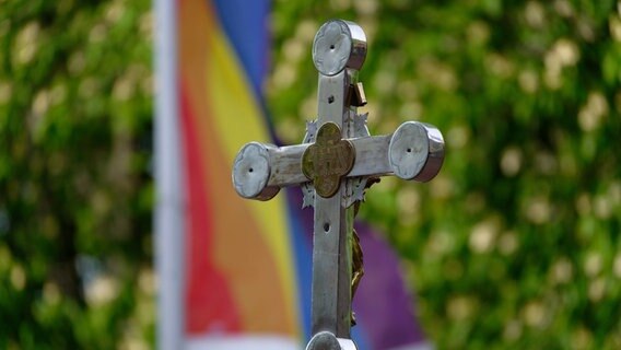 Ein kirchliches Kreuz vor einer Regenbogenfahne. © picture alliance/dpa/Henning Kaiser Foto: Henning Kaiser