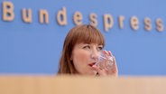 Heidi Reichinnek (Die Linke), Spitzenkandidatin und Co-Vorsitzende der Bundestagsgruppe, trinkt im Haus der Bundespressekonferenz auf einer Pressekonferenz ein Glas Wasser. © picture alliance Foto: Carsten Koall