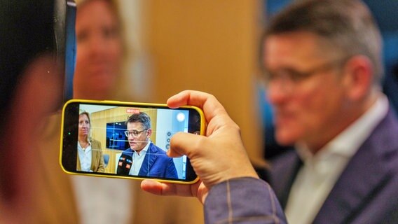 Der Ministerpräsident von Hessen, Boris Rhein (CDU, rechts), und die Fraktionsvorsitzende der CDU im Hessischen Landtag, Ines Claus (links)  sind auf einem Smartphone-Display zu sehen. © dpa Foto: Andreas Arnold
