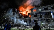 Feuerwehrleute arbeiten in einem Wohnblock in Saporischschja (Ukraine), der durch einen russischen Drohnenangriff beschädigt wurde. © Ukrinform/dpa Foto: Dmytro Smolienko