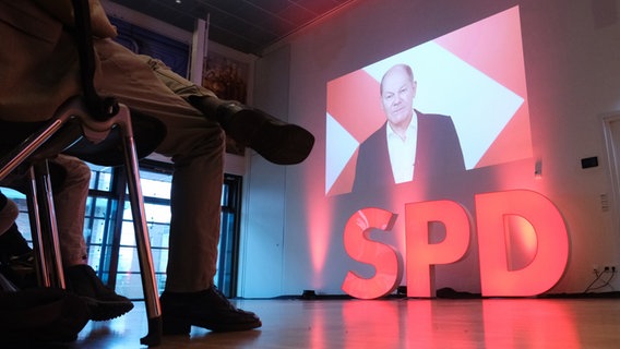 Bundeskanzler Olaf Scholz (SPD) ist in einer Videobotschaft auf einer Leinwand zu sehen. © dpa Foto: Sebastian Willnow