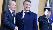 Der Präsident von Frankreich, Emmanuel Macron (Mitte), gibt Bundeskanzler Olaf Scholz (links) die Hand, als dieser im Elysee-Palast eintrifft. © AFP/dpa Foto: Ludovic Marin