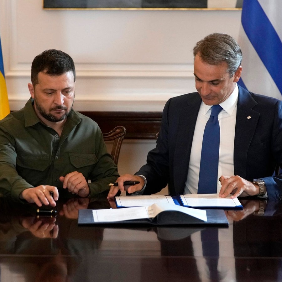 Der Präsident der Ukraine, Wolodymyr Selenskyj (links), und der Ministerpräsident von Griechenland, Kyriakos Mitsotakis (rechts), unterzeichnen während ihres Treffens in der Maximos-Villa in Athen (Griechenland) ein Abkommen. © AP/dpa Foto: Thanassis Stavrakis