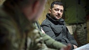 Der ukrainische Präsident Wolodymyr Selenskyj (rechts) hört während einer Besprechung mit der 27. Raketenartilleriebrigade zu, die an der Front in der Oblast Saporischschja kämpft. © Zuma Press/dpa Foto: Ukrainisches Präsidialamt