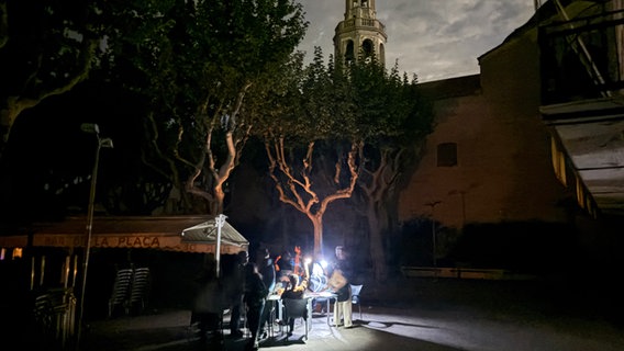 Auf der Placa de l'Ajuntament sitzen die Gäste eines Straßencafés in der Kleinstadt Premià de Mar bei Barcelona an der Kirche "San Cristòfol" bei einem Stromausfall im Licht von Taschenlampen und trinken lauwarmes Bier. © dpa Foto: Jan-Uwe Ronneburger