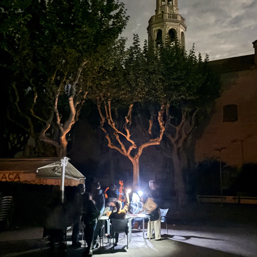 Auf der Placa de l'Ajuntament sitzen die Gäste eines Straßencafés in der Kleinstadt Premià de Mar bei Barcelona an der Kirche "San Cristòfol" bei einem Stromausfall im Licht von Taschenlampen und trinken lauwarmes Bier. © dpa Foto: Jan-Uwe Ronneburger