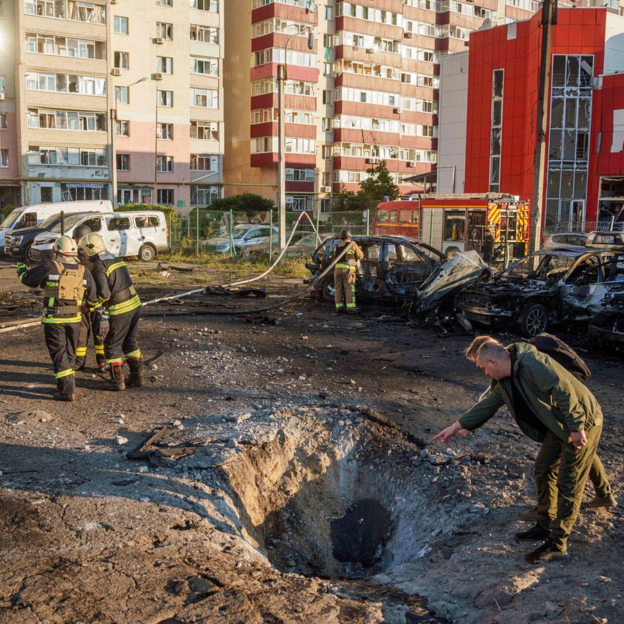 Einsatzkräfte der Feuerwehr betrachten den Krater nach einem russischen Luftangriff auf ein Wohnviertel in Sumy (Ukraine). © AP/dpa Foto: Evgeniy Maloletka