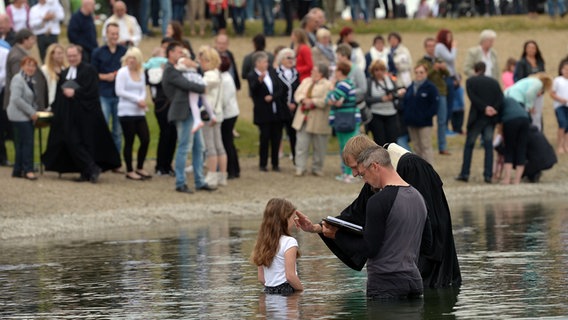 Ein Pastor tauft ein Mädchen im See. © picture alliance / dpa | Peter Steffen Foto: Peter Steffen