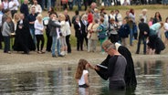 Ein Pastor tauft ein Mädchen im See. © picture alliance / dpa | Peter Steffen Foto: Peter Steffen