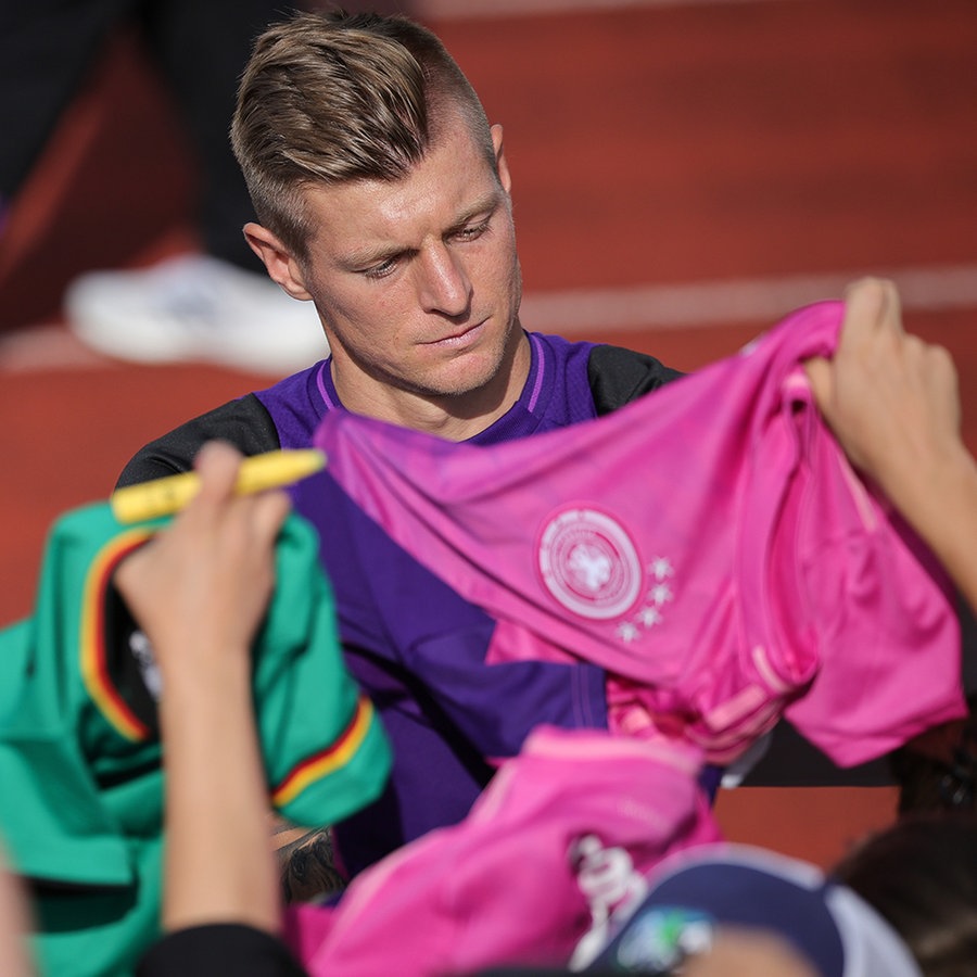 Deutschlands Toni Kroos gibt Fans Autogramme nach dem öffentlichen Training im Adi-Dassler-Stadion. © picture alliance Foto: Christian Charisius