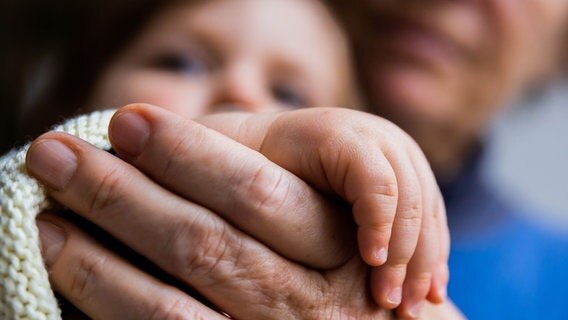 Die Hände von Enkelkind und Oma liegen ineinander © picture alliance/dpa | Christoph Soeder Foto: Christoph Soeder