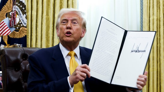 US-Präsident Donald Trump hält eine unterzeichnete Durchführungsverordnung im Oval Office des Weißen Hauses. © picture alliance/dpa/Pool | Uncredited 