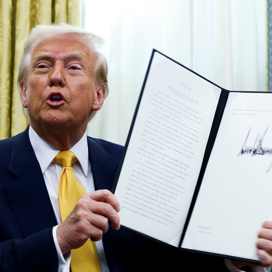 US-Präsident Donald Trump hält eine unterzeichnete Durchführungsverordnung im Oval Office des Weißen Hauses. © picture alliance/dpa/Pool | Uncredited 