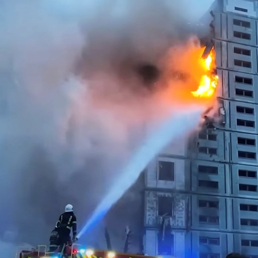 Feuerwehrmänner löschen ein durch eine Rakete in Brand geratenes Wohnhaus. © picture alliance/dpa/National Police of Ukraine 