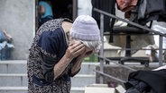 Ukraine: Eine alte, erschöpfte Frau hält ihren Kopf in den Händen © picture alliance / AA Foto: Narciso Contreras