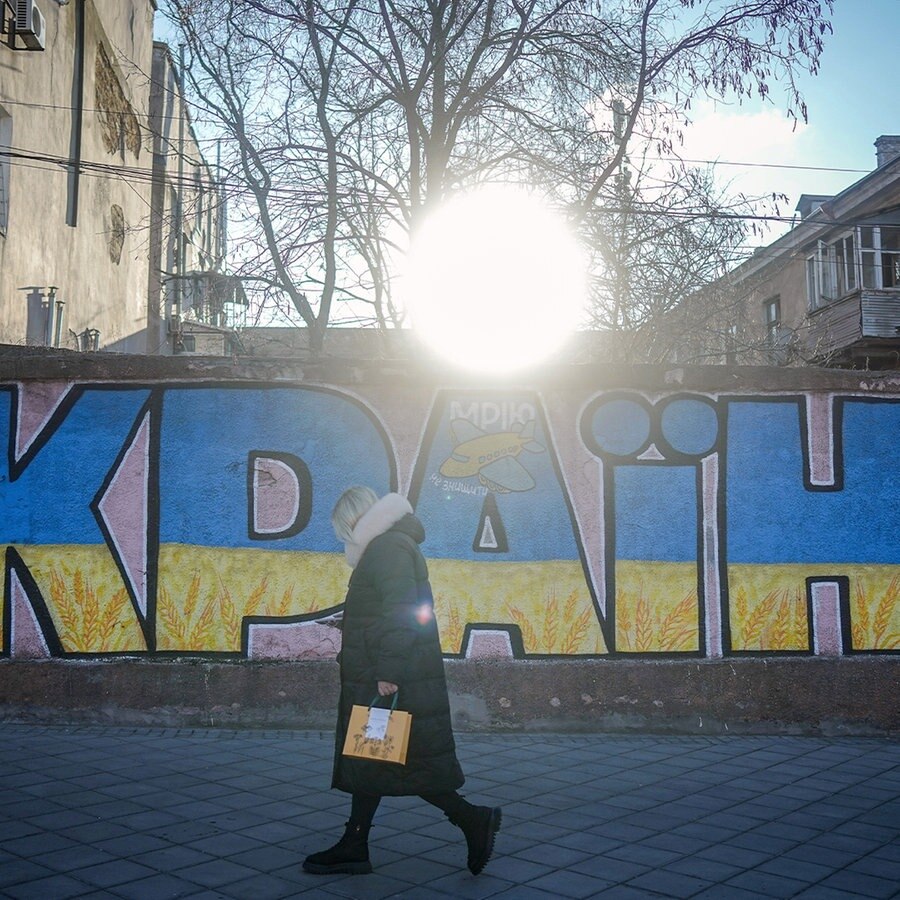 Eine Frau geht an einem Ukraine Graffiti in der Hafenstadt vorbei. Am 24. Februar 2024 jährt sich der Beginn des russischen Angriffskrieges gegen die Ukraine zum zweiten Mal. © picture alliance/dpa Foto: Kay Nietfeld