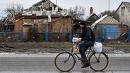Ein Mann fährt Fahrrad, nachdem er Hilfsgüter von einer Verteilungsstelle für humanitäre Hilfsgüter in Orichiw erhalten hat. Orikhiv ist eine kleine Stadt in der Nähe von Saporischschja. © Sipa USA | SOPA Images 