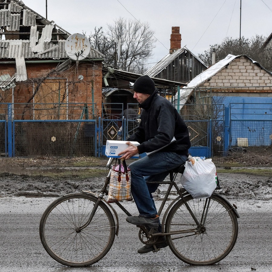 Ein Mann fährt Fahrrad, nachdem er Hilfsgüter von einer Verteilungsstelle für humanitäre Hilfsgüter in Orichiw erhalten hat. Orikhiv ist eine kleine Stadt in der Nähe von Saporischschja. © Sipa USA | SOPA Images 