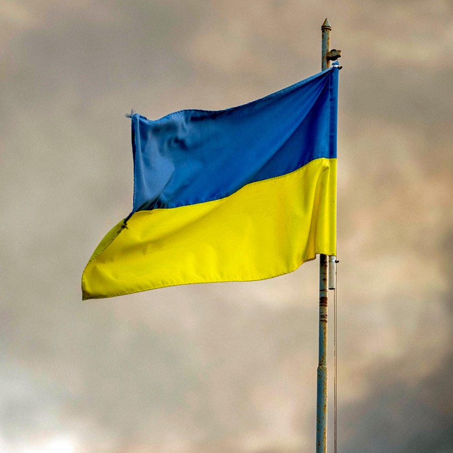 Die ukrainische Flagge ist vor dem Rauch eines Feuers zu sehen, nach russischen Angriffen auf Kiew. © ZUMA Press Wire/dpa Foto: Andreas Stroh