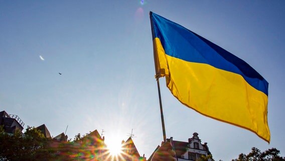 Jemand hält eine ukrainische Flagge hoch. © dpa Foto: Thomas Banneyer