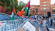 Menschen versammeln sich bei einem propalästinensischen Lager auf dem Campus der George Washington University. © XinHua/dpa Foto: Aaron Schwartz