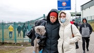 Eine ukrainische Familie geht in Medyka durch den Grenzübergang nach Polen. © dpa-Bildfunk 