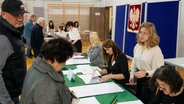 Menschen warten auf die Stimmabgabe in einem Wahllokal während der Parlamentswahl. © picture alliance 