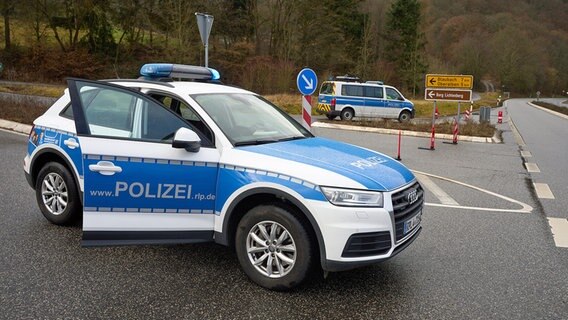 Ein Polizeiauto steht mit geöffneter Beifahrertür auf einer Kreuzung als Absperrung bei einem Polizeieinsatz. © dpa bildfunk Foto: Thomas Frey