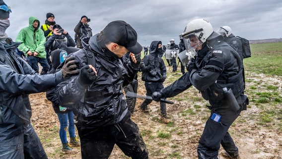 Ein Polizist geht mit einem Schlagstock gegen einen Demonstranten vor dem Dorf Lützerath vor. © Jochen Tack Foto: Jochen Tack