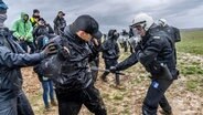 Ein Polizist geht mit einem Schlagstock gegen einen Demonstranten vor dem Dorf Lützerath vor. © Jochen Tack Foto: Jochen Tack