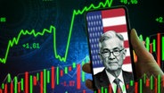 Jerome Powell, Chef der Federal Reserve System (FED), bzw. US-Notenbank auf einem Handy vor einer US-Flagge. Im Hintergrund werden Börsencharts angezeigt - Fotomontage
Aufnahmedatum Handy vor einer USA-Flagge. Symbolik Reden & Entscheidungen durch den Notenbank-Chef und Auswirkungen auf US-Dollar und Aktien. Fotomontage © picture alliance / CHROMORANGE Foto: Michael Bihlmayer