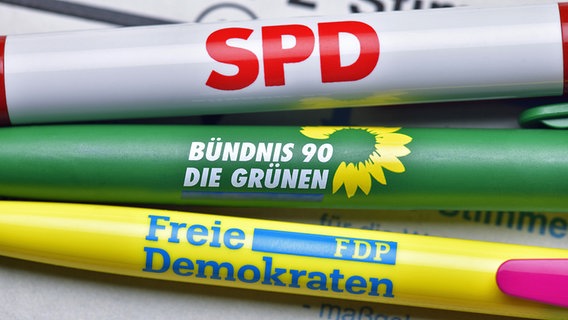 Drei Parteien-Kugelschreiber von der SPD, den Grünen und der FDP liegen auf einem Stimmzettel und bilden zusammen eine Ampel-Koalition. © picture alliance / CHROMORANGE Foto: Christian Ohde