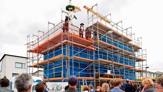 Männer stehen bei einem Richtfest auf dem Dach. © Gundlach 
