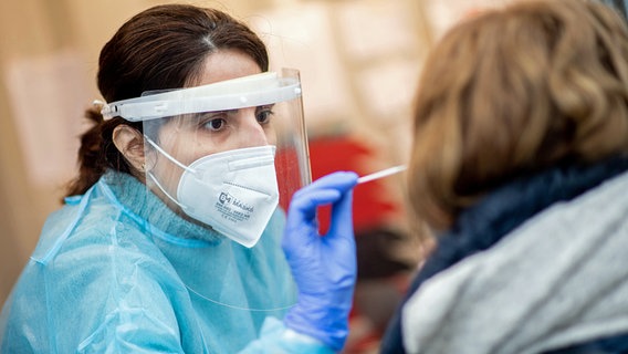Eine Mitarbeiterin einer Teststation nimmt einen Abstrich aus der Nase von einer Frau. © picture alliance/dpa Foto: Hauke-Christian Dittrich