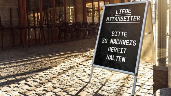 Ein Straßensteller am Eingang weist Arbeitnehmer auf einen 3G-Nachweis während der Corona-Pandemie hin. © imago images/Bihlmayerfotografie 