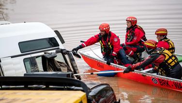 Erfstadt (Nordrhein-Westfalen). Helfer der Wasserwacht untersuchen von einem Boot aus Lastwagen, die auf der überfluteten Bundesstraße 265 stehen. © dpa-Bildfunk Foto: Marius Becker/dpa