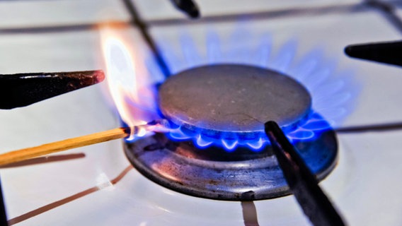 Eine Gasflamme wird mit einem Streichholz in einem Gasherd angezündet. © imago images/teamwork Foto: Ute Klaphake