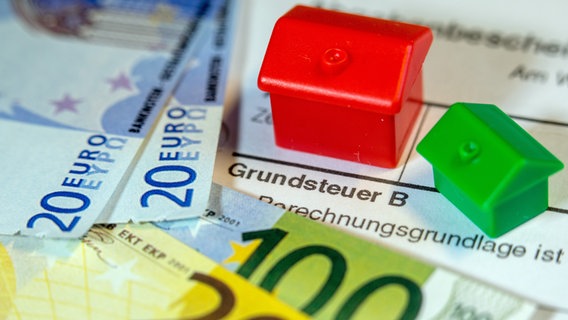 Ein grünes und ein rotes Spielzeughaus und die Nachbildung von Euro-Geldscheinen liegen auf einem Abgabenbescheid für die Entrichtung der Grundsteuer. © picture alliance/dpa/dpa-Zentralbild Foto: Jens Büttner